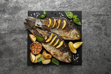 Photo of Tasty homemade roasted crucian carps served on grey table, top view. River fish