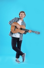 Photo of Young man playing acoustic guitar on color background