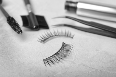 Photo of False eyelashes and cosmetic tools on grey background, closeup