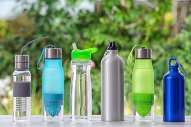 Photo of Sports water bottles on table against blurred background