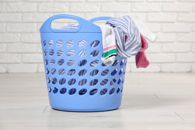 Laundry basket with clothes near white brick wall