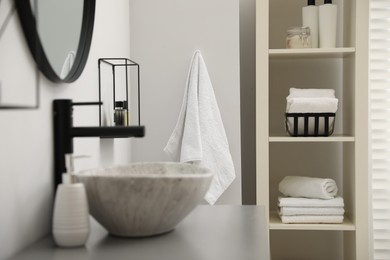 Photo of Shelving unit with stacked clean towels in bathroom