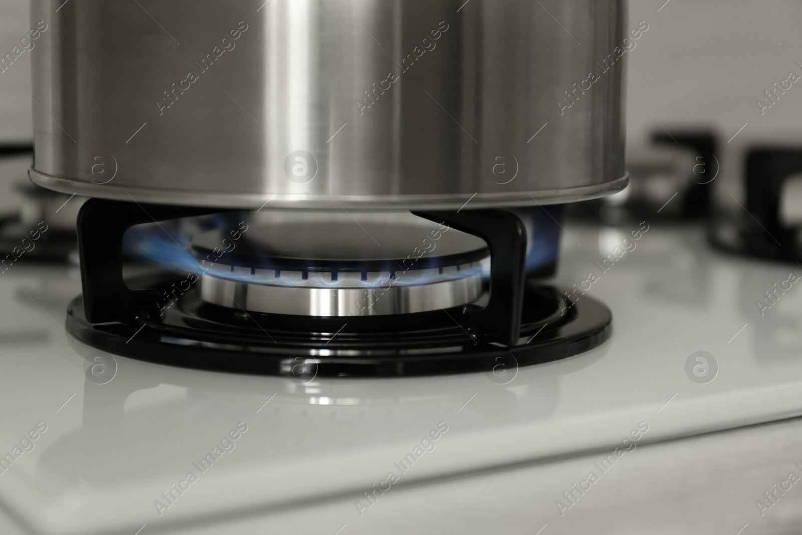 Photo of Steel kettle on modern gas stove, closeup