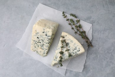 Photo of Tasty blue cheese with thyme on grey table, top view
