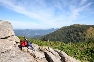 Photo of Sleeping bag and trekking poles on mountain peak, space for text