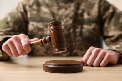 Photo of Law concept. Man in military uniform with gavel at wooden table, closeup