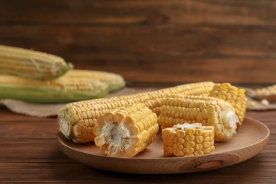 Photo of Plate with tasty sweet corn on wooden table