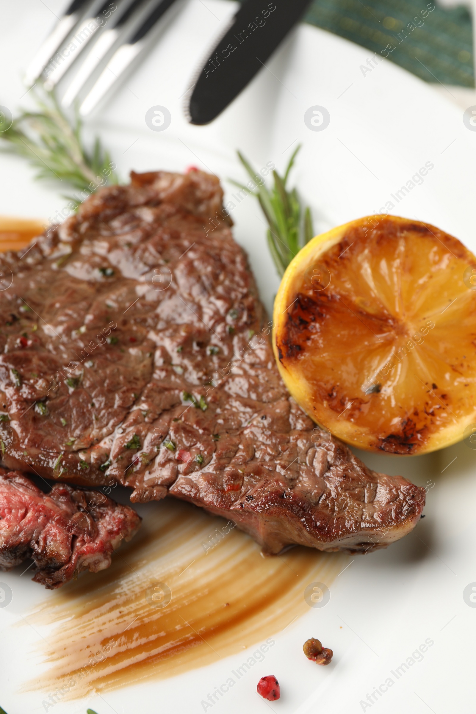 Photo of Delicious grilled beef steak with spices and lemon on plate, closeup