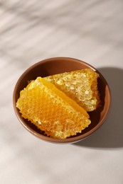Photo of Natural honeycombs in bowl on white table, above view