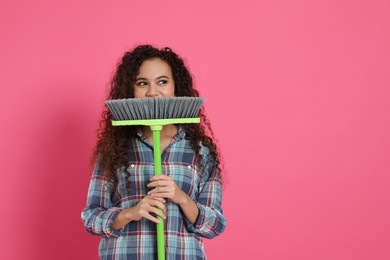 Photo of African American woman with green broom on pink background, space for text