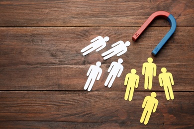 Photo of Magnet attracting people traffic on wooden background, top view with space for text. Marketing concept