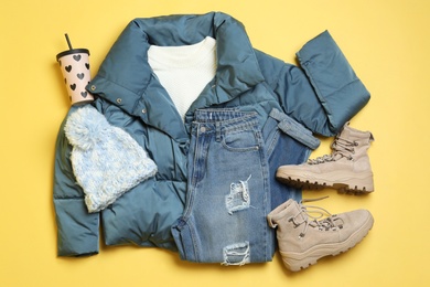 Flat lay composition with winter clothes and boots on yellow background