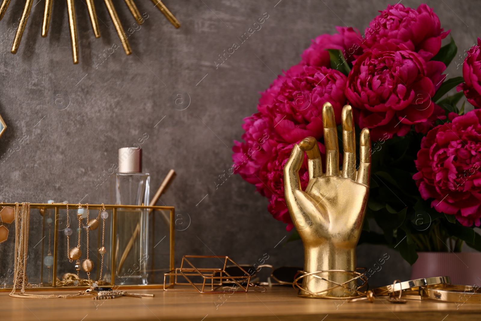 Photo of Composition with gold accessories and flowers on dressing table near grey wall