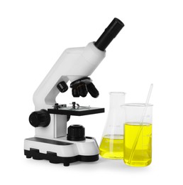 Photo of Laboratory glassware with yellow liquid and microscope isolated on white