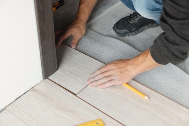 Photo of Worker installing new laminate flooring in room, closeup