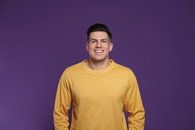Photo of Handsome man laughing on purple background. Funny joke