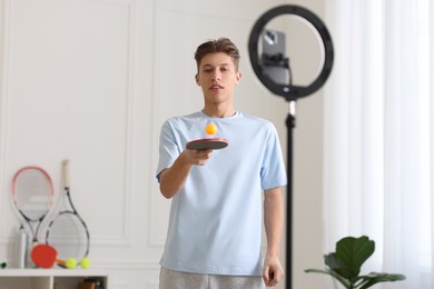 Photo of Sports blogger with table tennis racket and ball streaming online fitness lesson at home