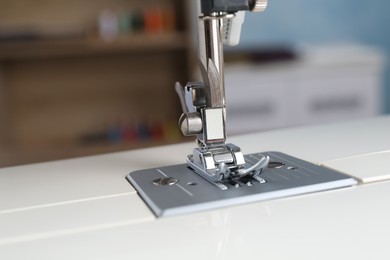 Photo of White sewing machine on blurred background, closeup