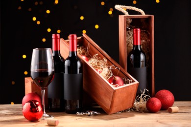 Photo of Bottles of wine, glass, wooden boxes, corks and red Christmas balls on table