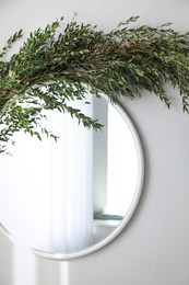Photo of Mirror decorated with green eucalyptus on white wall