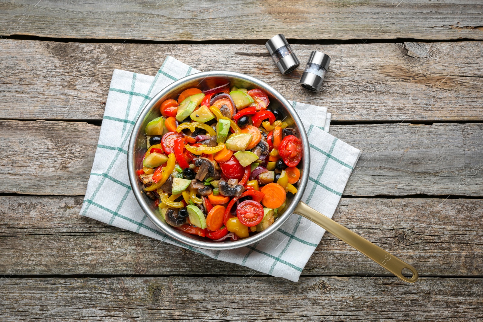 Photo of Frying pan with tasty cooked vegetables and mushrooms on wooden table, flat lay