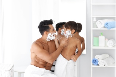 Photo of Father and son having fun while shaving in bathroom