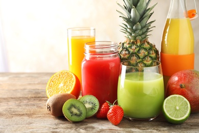 Photo of Glassware with different juices and fresh fruits on wooden background