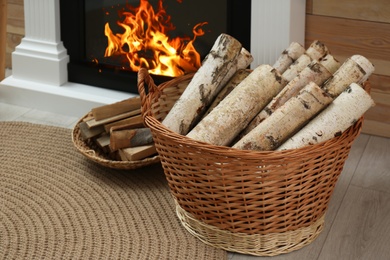 Photo of Firewood in wicker baskets near fireplace indoors
