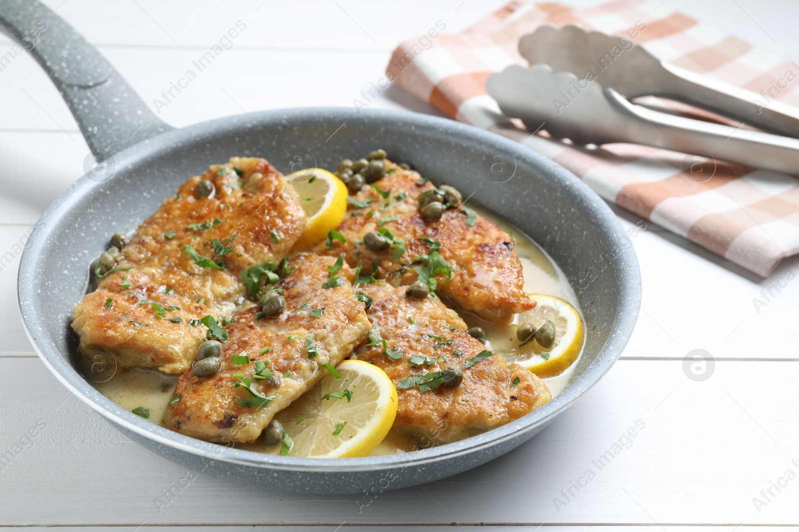 Photo of Delicious chicken piccata on white wooden table, closeup