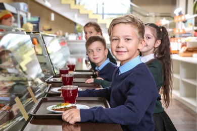 Photo of Children near serving line with healthy food in school canteen