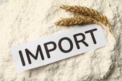 Photo of Card with word Import on wheat flour, top view