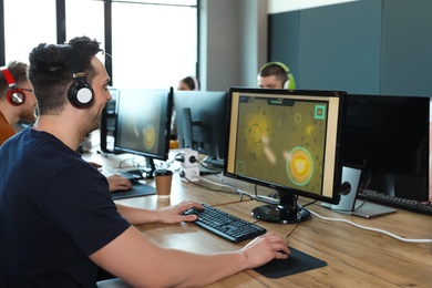 Photo of Man playing video game in internet cafe