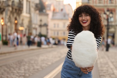 Photo of Portrait of happy woman with cotton candy on city street. Space for text
