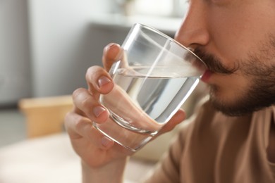 Photo of Man drinking water at home, closeup. Refreshing beverage