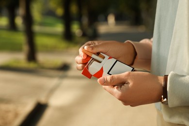 Photo of Woman taking cigarette out of pack outdoors, closeup