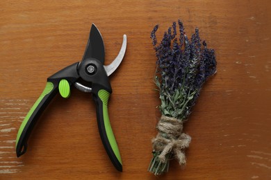 Photo of Secateur and beautiful lavender on wooden table, flat lay