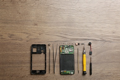 Photo of Disassembled mobile phone and repair tools on table, flat lay. Space for text