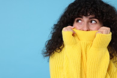 Photo of Young woman in stylish yellow sweater on light blue background, space for text