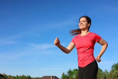 Photo of Young woman listening to music while running outdoors in morning. Space for text