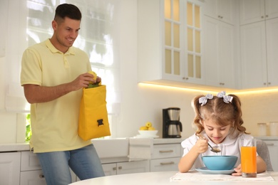 Photo of Father helping his little child get ready for school in kitchen