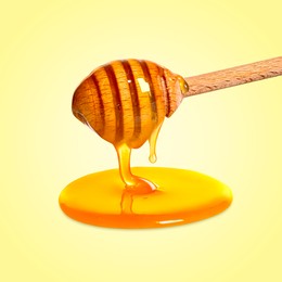 Image of Natural honey dripping from dipper on yellow background