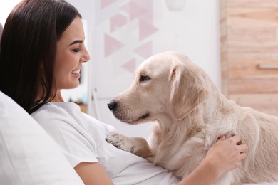 Photo of Young woman and her Golden Retriever dog on bed at home