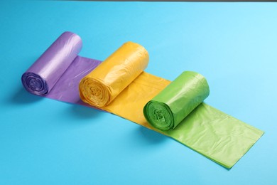 Photo of Rolls of different garbage bags on light blue background