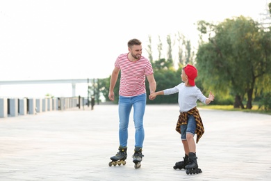 Photo of Father and son roller skating on city street