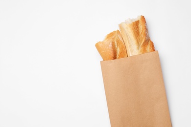 Photo of Paper bag with bread on white background, top view. Space for text