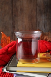 Photo of Cup of hot drink on stack of books against wooden background. Cozy autumn atmosphere