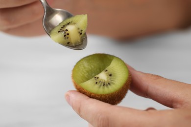 Photo of Man eating kiwi with spoon on blurred background, closeup