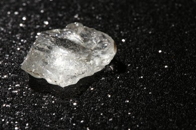 Photo of Beautiful rough diamond on dark shiny background, closeup. Space for text