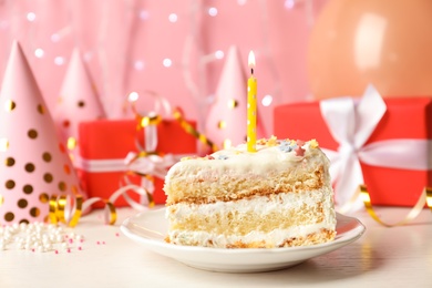 Photo of Slice of delicious birthday cake with candle on table