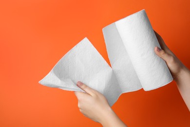 Photo of Woman tearing paper towels on orange background, closeup